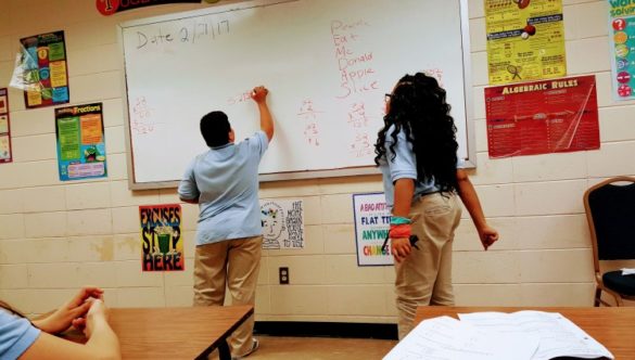 students solving math problems at a white board