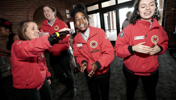 AmeriCorps members dancing and singing into a microphone