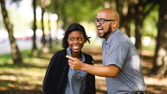 Two AmeriCorps members share a laugh at a city park.