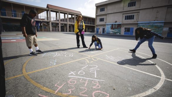 students are doing math problems in chalk on playground with AmeriCorps member