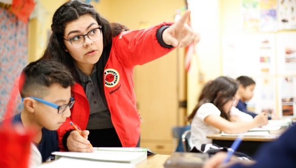 city year americorps member pointing at something as a student looks on