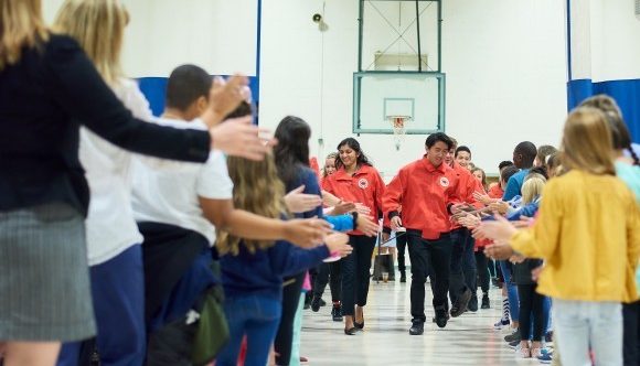 AmeriCorps members coming down a line up of students in a gymnasium giving the students high fives