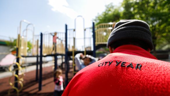 AmeriCorps member is on playground with students while they play
