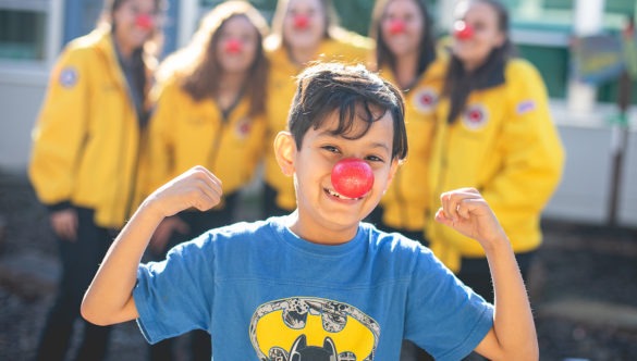 A student with City Year AmeriCorps members red nose day